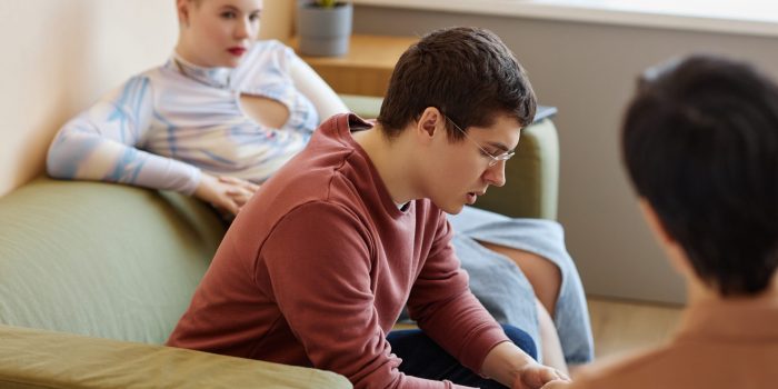 Young couple discussing problems with psychologist during session in office